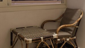 A room with a view of pyramids through a window, a wicker chair, and a small table. - Hana Giza Pyramids Inn (Giza)
