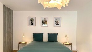 A modern bedroom with a large bed, two bedside tables with lamps, and three framed artworks on the wall. - The Impressionist Villa (Vernon)