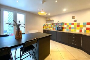 Une cuisine moderne dotée d’un îlot central, de meubles de rangement noirs et d’un revêtement mural coloré.