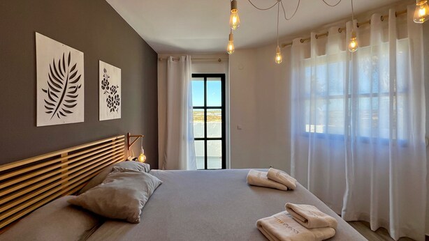 A modern bedroom with a large bed, wooden headboard, and two wall art pieces.