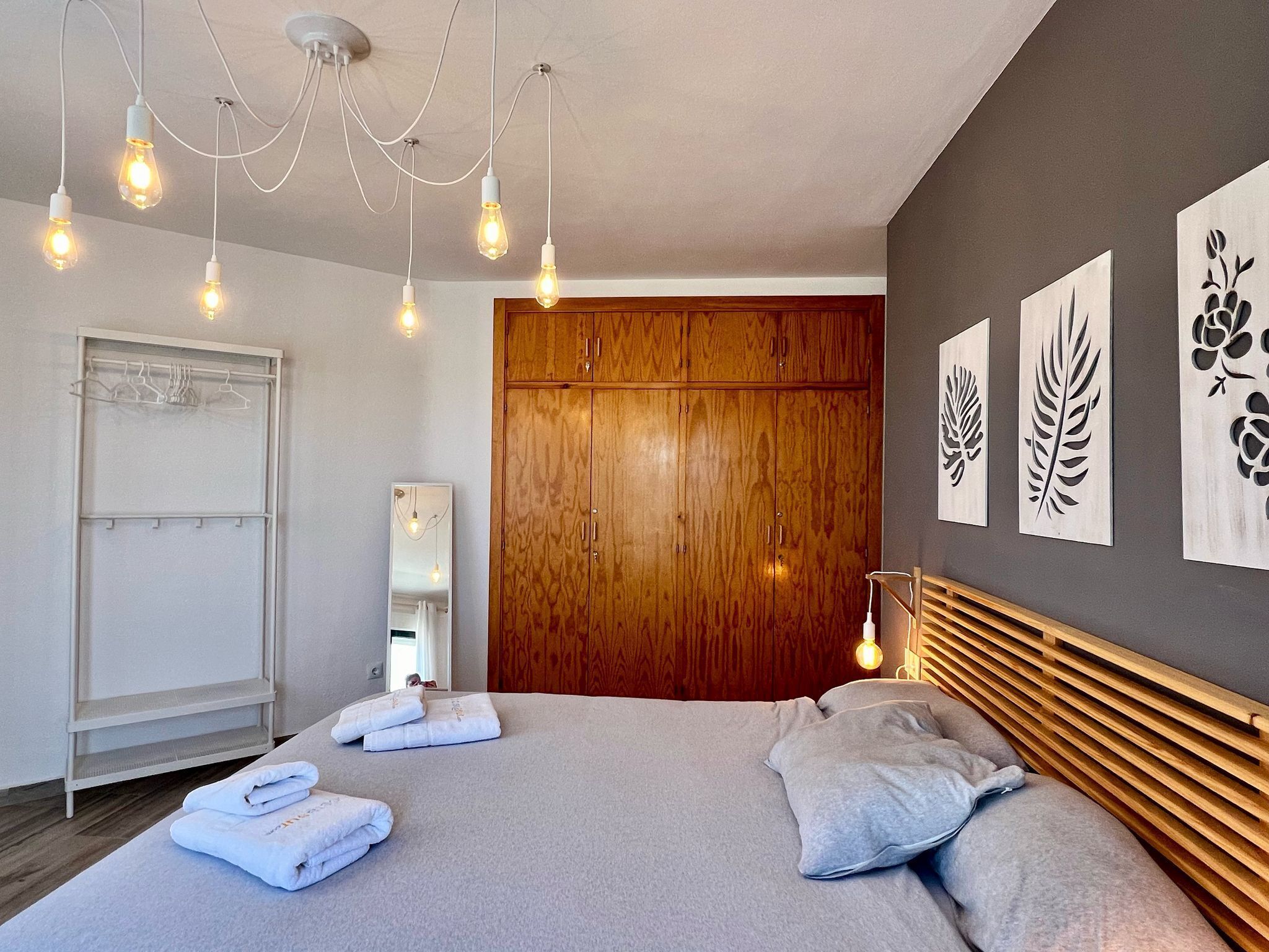 Une chambre moderne avec un grand lit, une armoire en bois et des œuvres d’art murales.