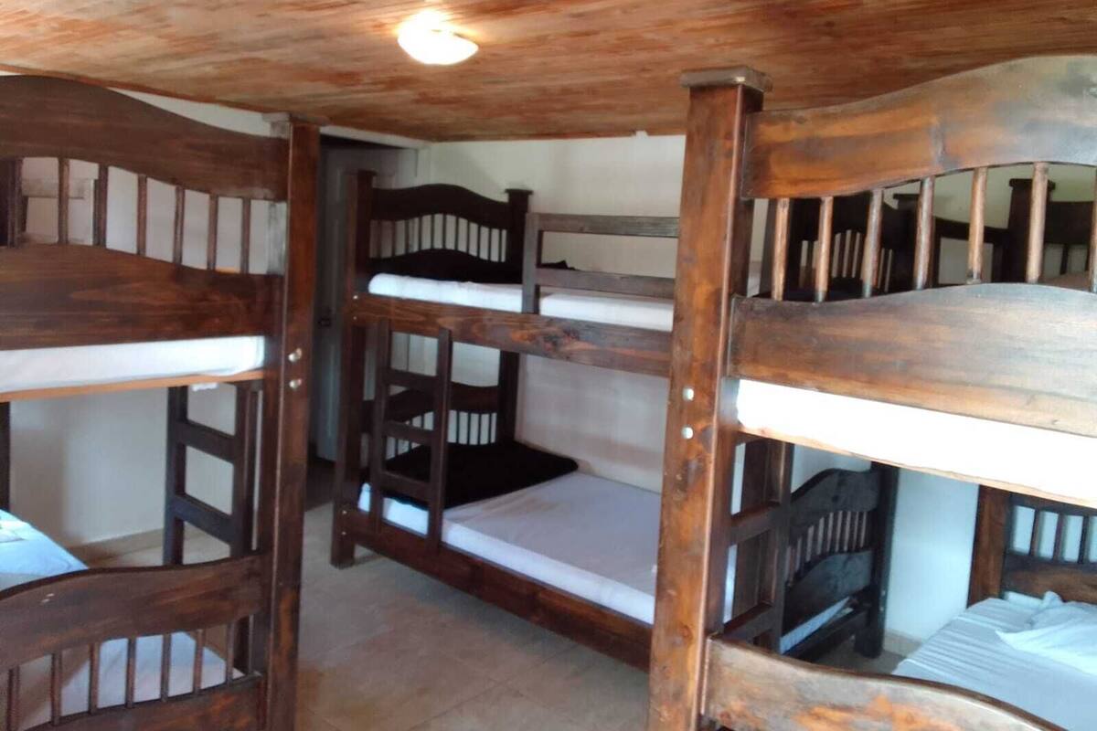 A bunk bed room with wooden frames and white bedding.