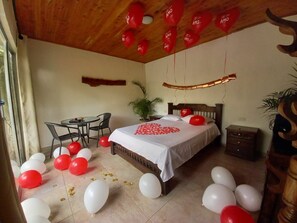 A bedroom with a bed, a desk, and chairs. There are balloons on the floor and ceiling. - hostal hilltop salento (Salento)