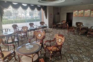 A hotel room with a patterned carpet, wicker furniture, and a view of the outdoors.
