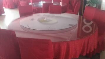 A round table with a glass top, surrounded by red chairs.