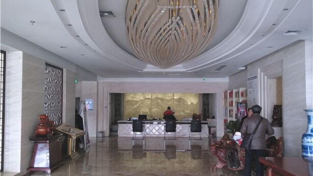Eine Hotelhalle mit einer Rezeption, einer großen Chandelüster und einer Wandverzierung.