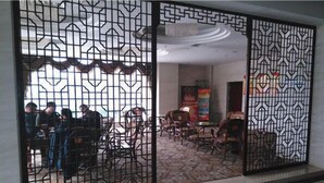 Ein Zimmer mit einer gemusterten Trennwand, einem Fliesenboden und einer Sitzecke mit Stühlen und Tischen.