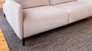 Ein modernes Wohnzimmer mit Sofa, Esstisch und Küchenbereich mit Holzausstattung und Mikrowelle.
