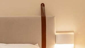 Ein Bett mit weißem Kopfteil und einem braunen Riemen.