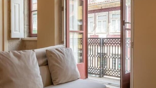 Ein Zimmer mit einer Couch, einem großen Fenster und einem Balkon.