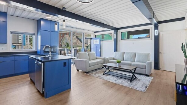 Una cocina moderna con armarios azules, una isla central y un área de comedor con sofá y mesa de centro.