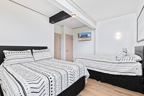 A modern bedroom with two beds, a TV on the wall, and a ceiling light. - Stadium Container Club House (Indianapolis)