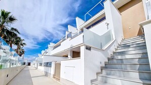 A modern residential building with a white facade, a balcony, and a staircase leading to the entrance. - Penthouse with private roof terrace (Mar de Cristal)