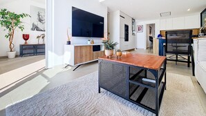 A modern living room with a large flat-screen TV, a wooden dining table, and a seating area with a sofa and chairs. - Penthouse with private roof terrace (Mar de Cristal)