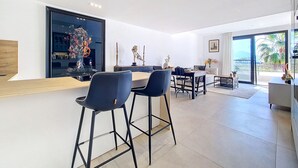 A modern kitchen with a central island, bar stools, and a dining area with a table and chairs. - Penthouse with private roof terrace (Mar de Cristal)