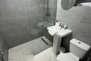Enjoy a functional and clean bathroom with a glass-enclosed shower, pedestal sink, and toilet.