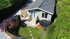 Una casa de dos plantas con porche delantero, una pequeña terraza y un jacuzzi.