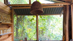 Una cocina rústica con armarios de madera, una estufa a gas y una ventana con vistas a exuberante vegetación.