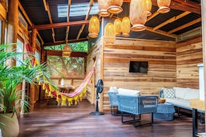 A wooden cabin interior with a hammock, wicker furniture, and hanging lanterns. - La Casa del Mono (Santa Marta)