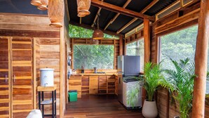 Interior de una cabaña de madera con cocina, comedor y ventanas amplias.