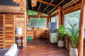 Interior de una cabaña de madera con cocina, comedor y ventanas amplias.
