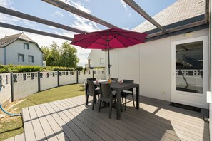 A patio with a table and chairs, a red umbrella, and a view of a house. - House near the sea AOD, 300m from the beach for 5 people (Damgan)