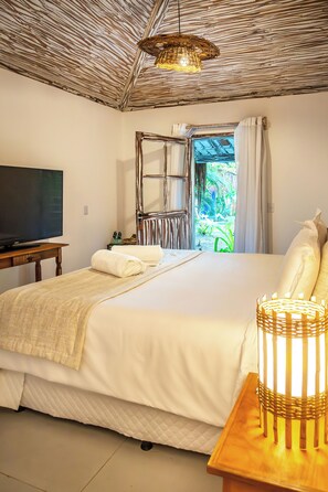 A bedroom with a bed, a television, a window with curtains, and a ceiling fan.