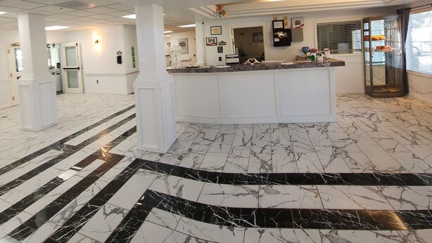 A spacious lobby with a marble floor, a reception desk, and a staircase leading to an upper level. - The Enchanted Suites & Residence  (Roswell)