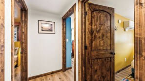 A hallway with wooden doors, a framed picture on the wall, and a yellow wall.
