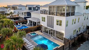 Une maison moderne à plusieurs étages, dotée d’un grand jardin comprenant une piscine et un espace salon extérieur.