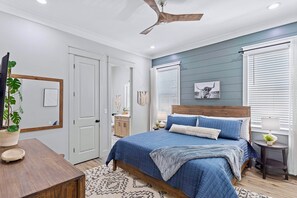 A bedroom with a bed, bedside tables, a ceiling fan, and a window with blinds.