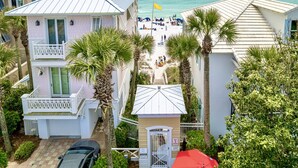 Une propriété située en bord de mer, comprenant plusieurs bâtiments, une plage animée et des palmiers.