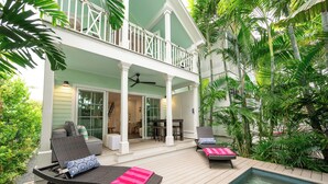 A poolside area with lounge chairs, a pool, and a covered patio with a dining area.