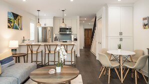 A modern kitchen with white cabinets, stainless steel appliances, and a central island with bar stools.