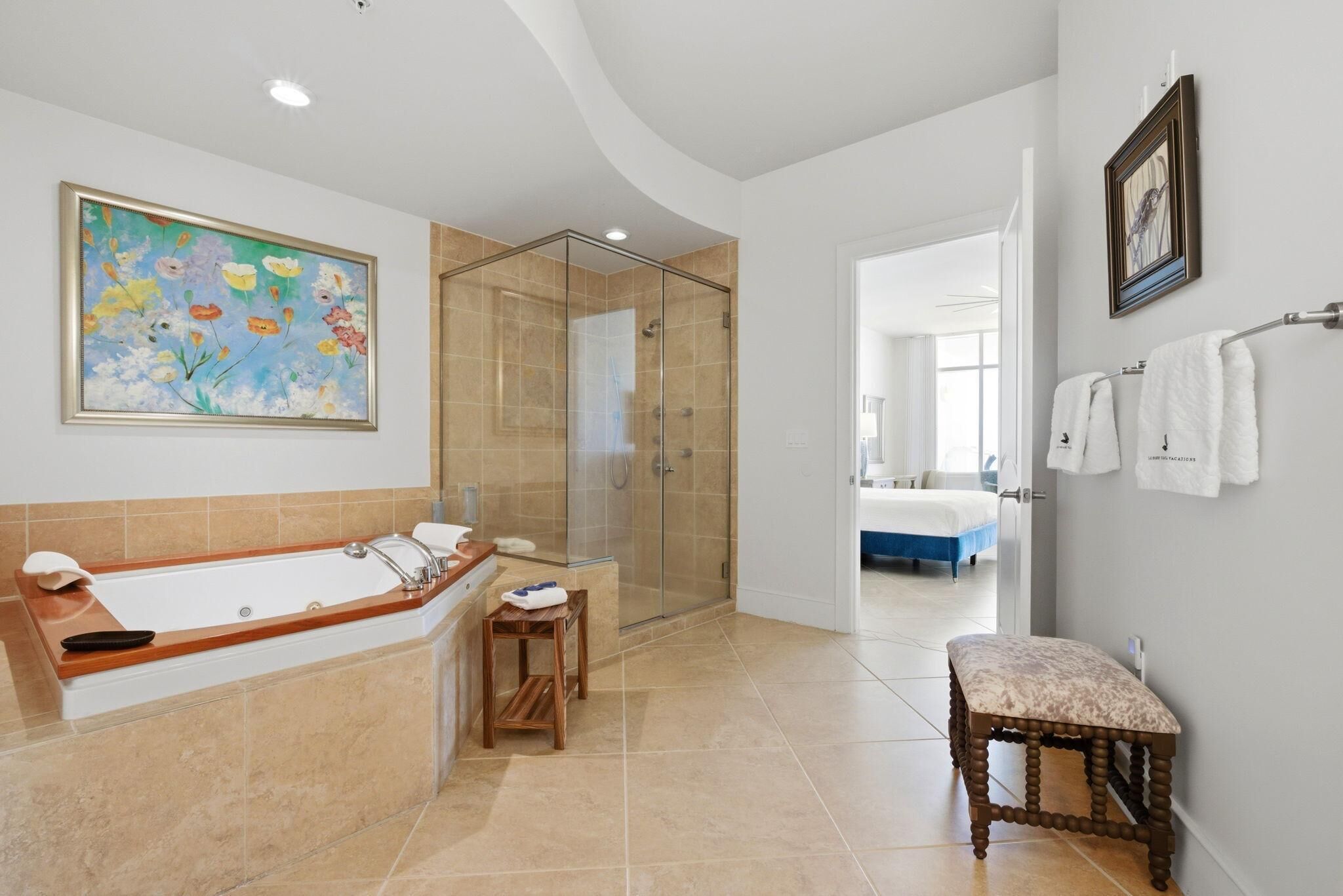 A bathroom with a large bathtub, a shower, a wooden stool, and a bench.