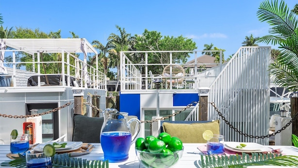 A dining area with a table set for two, featuring a pitcher of blue drink, a bowl of green fruit, and a glass of blue drink. - Modern Lush Green Escape (Fort Lauderdale)