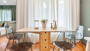 A dining area with a wooden table, clear chairs, a vase with flowers, and sheer curtains. - Modern Lush Green Escape (Fort Lauderdale)