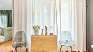 A room with a wooden cabinet, two clear plastic chairs, and a white curtain backdrop. - Modern Lush Green Escape (Fort Lauderdale)