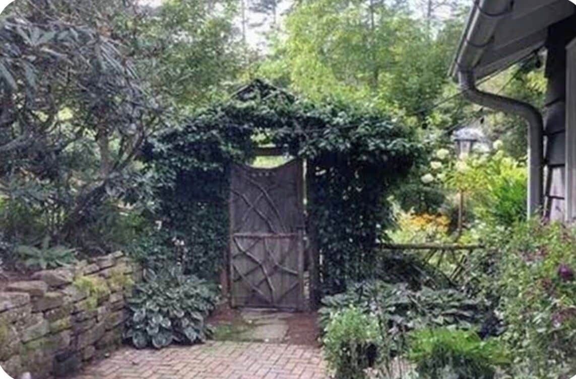 Een poort met een met baksteen bestraat pad dat naar een gebouw leidt.
