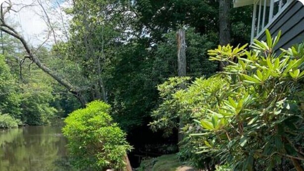 Eine Holzterrasse mit Gartenmöbeln, darunter eine Couch und Stühle, mit Blick auf ein Gewässer.