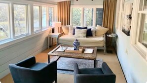 Ein gemütliches Zimmer mit einem Bett, zwei Stühlen, einem Couchtisch und einem fenster mit Vorhängen.