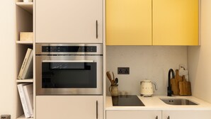 A modern kitchen with a built-in oven, a coffee maker, and a sink. - Cozy Suite in Sloane Square (London)