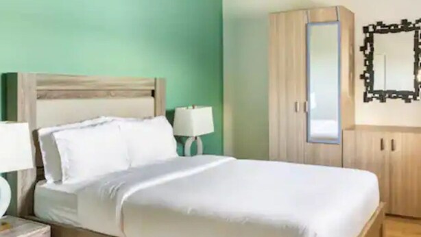 Een slaapkamer met een bed, nachtkastjes, een kledingkast en een spiegel.