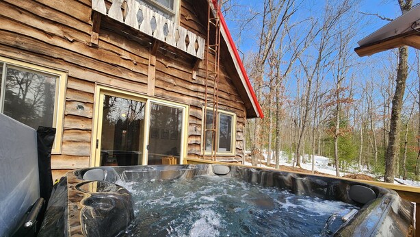 A wooden cabin with a hot tub in front. - Hawkins Hideout  Cabin, Starlink Wi-Fi, Hot Tub! (Reed City)