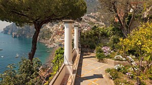 Un pueblo costero con una escalera que baja al mar, rodeado de árboles y edificios.