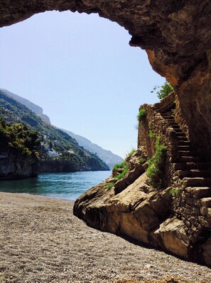 A coastal view through a rocky archway overlooking a beach and a mountainous landscape. - Torre Sponda - Cisterna Private Beach (Positano)