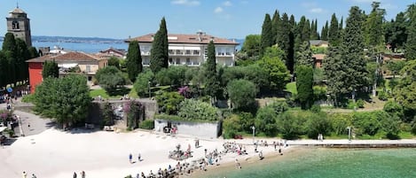 A coastal area with a beach, clear water, and a large building with a tower.