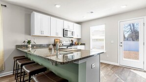A modern kitchen with white cabinets, a granite countertop, and a built-in island with bar stools.