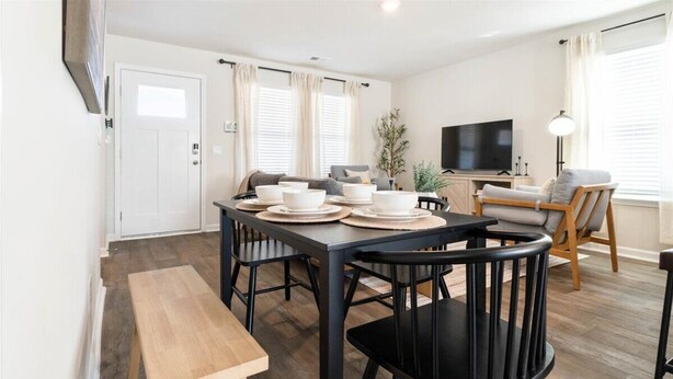 A dining area with a table set for four, a bench, and a TV in the background.