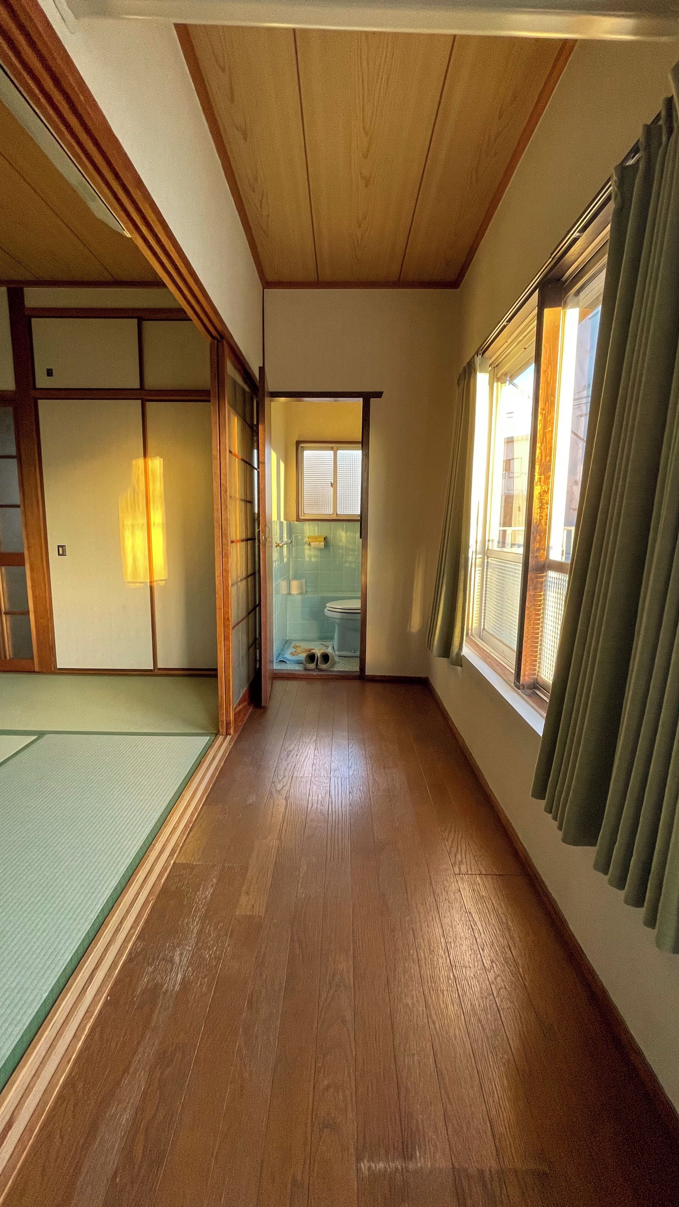 A traditional Japanese room with tatami flooring, sliding doors, and a view of a bathroom.
